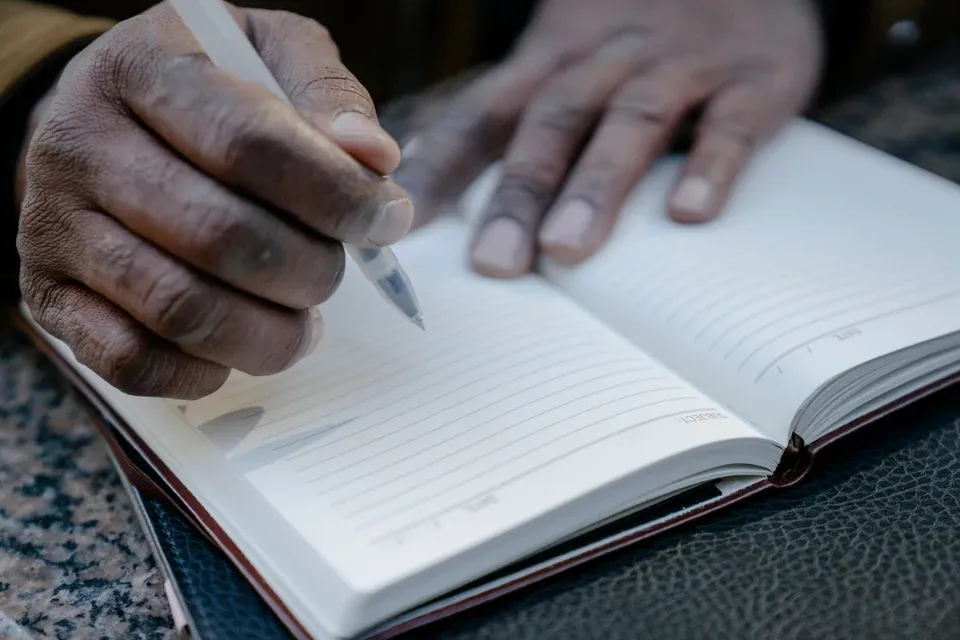 Primer plano de una persona escribiendo en un cuaderno.
