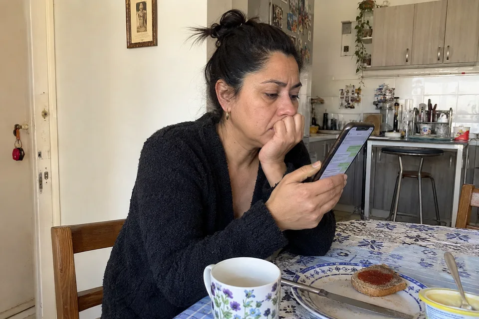 Una mujer vuelve a comprobar un mensaje mientras deja su desayuno a un lado.