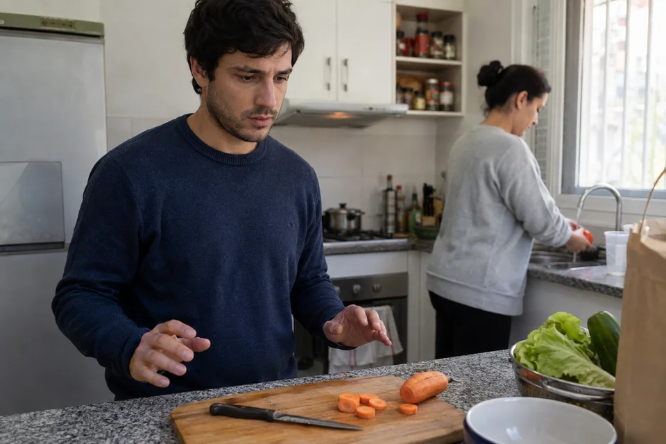 Joven interrumpe la preparación de comida y se aparta con preocupación del cuchillo apoyado sobre la tabla
